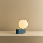 Opal globe table lamp with wall mount option, Sapphire, on a shelf, lit