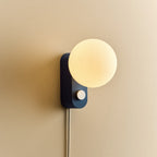 Opal globe table lamp with wall mount option, Sapphire, mounted on a wall, lit