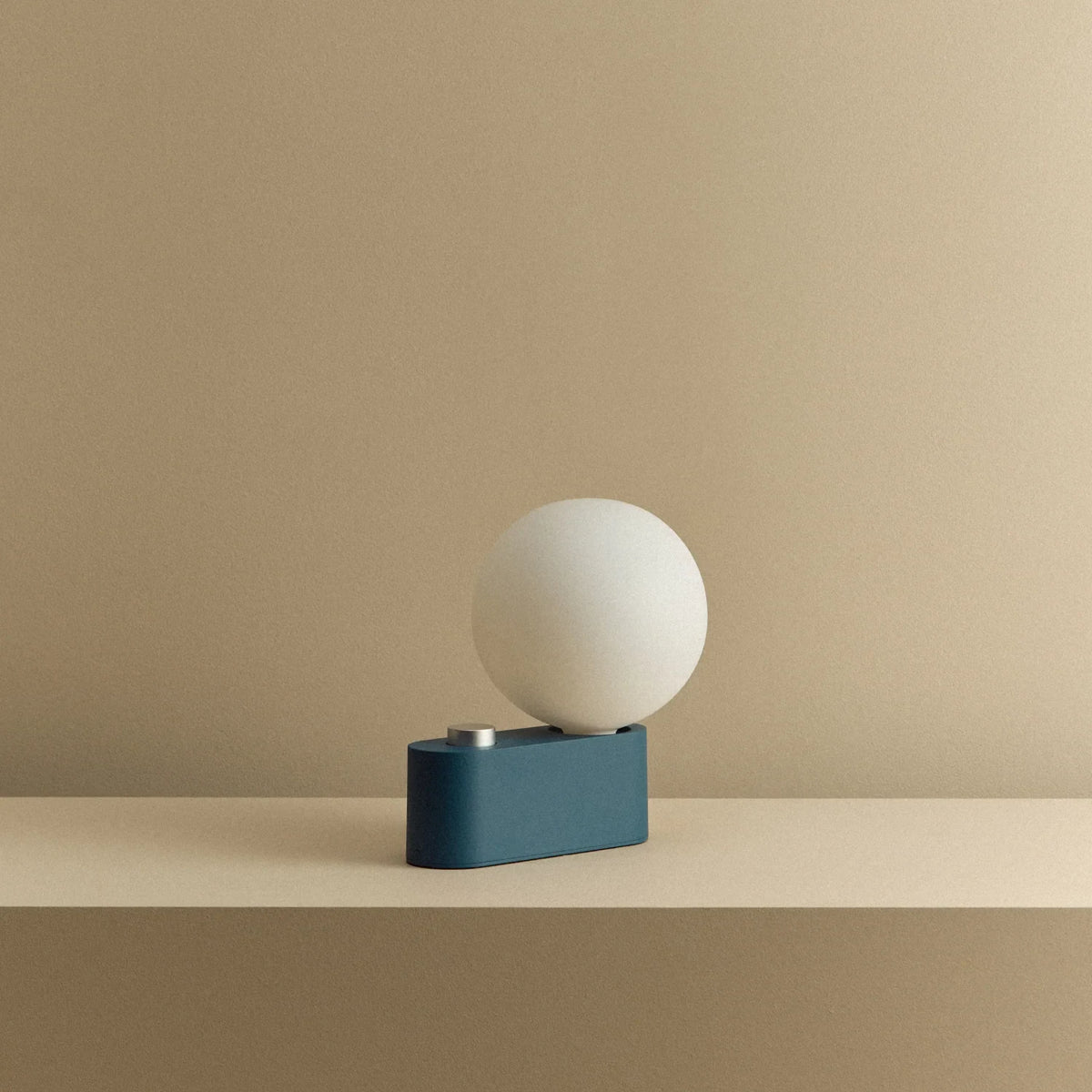 Opal globe table lamp with wall mount option, Sapphire, on a shelf, unlit