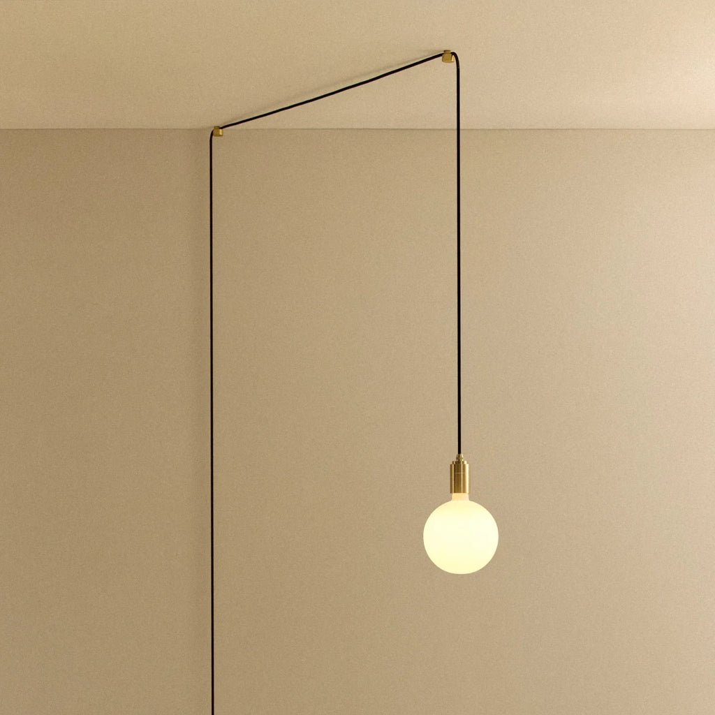 Opal sphere bulb plug-in pendant, in brass, routed across the ceiling and down the wall