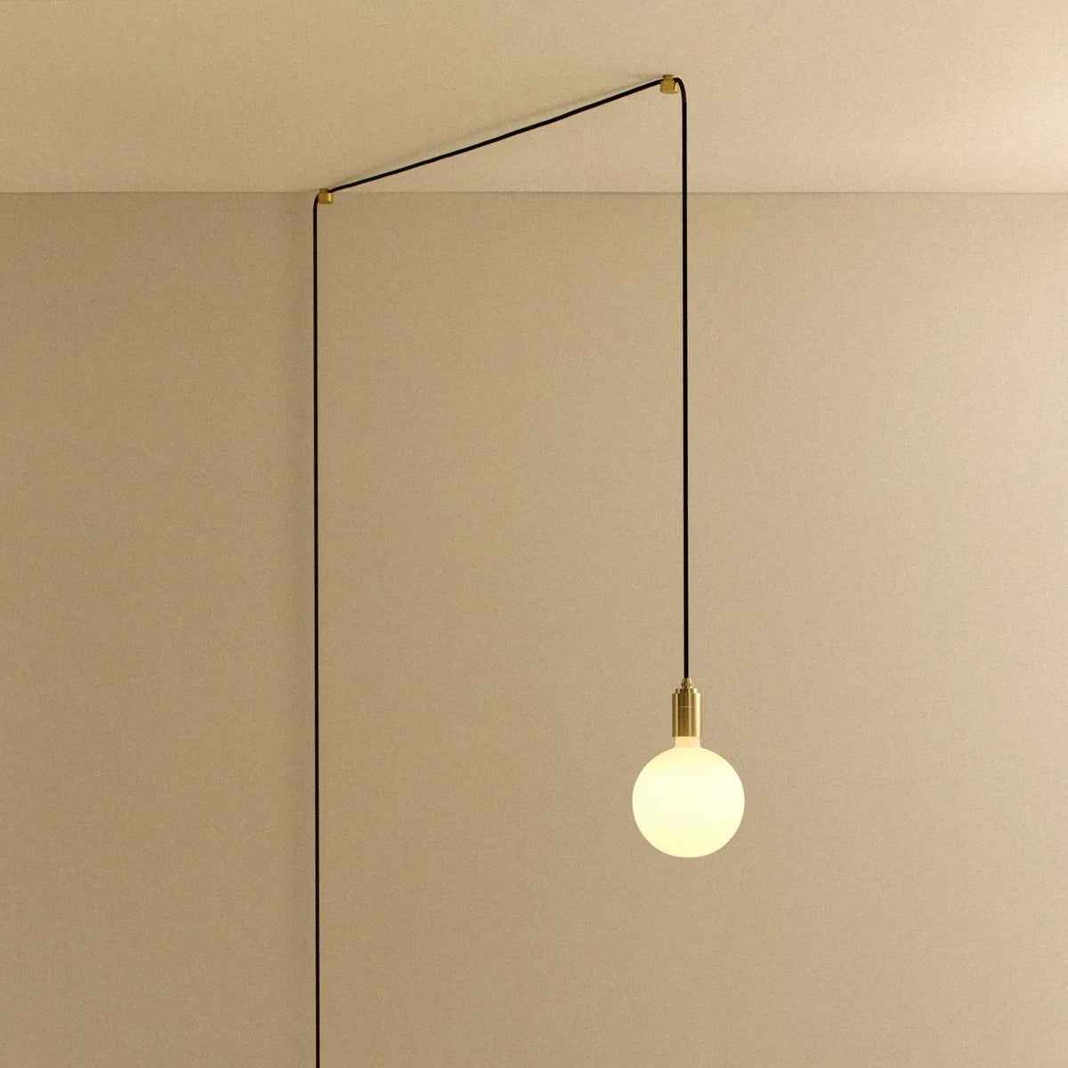 Opal sphere bulb plug-in pendant, in brass, routed across the ceiling and down the wall
