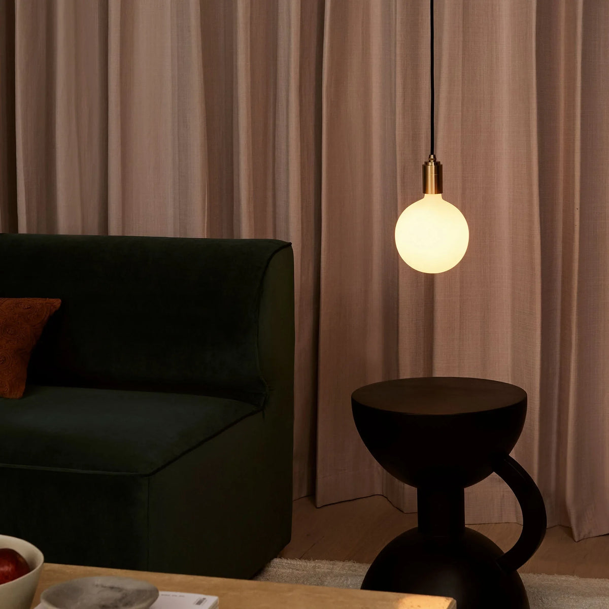 Opal sphere bulb plug-in pendant, lit beside an armchair