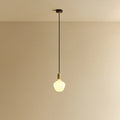 Opal trapezoid bulb pendant, in brass, lit, against a plain wall