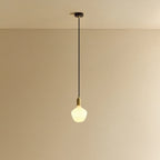 Opal trapezoid bulb pendant, in brass, lit, against a plain wall