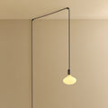 Plug-in pendant with oval matte white bulb, graphite, lit, hung from a wall node