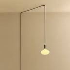 Plug-in pendant with oval matte white bulb, graphite, lit, hung from a wall node