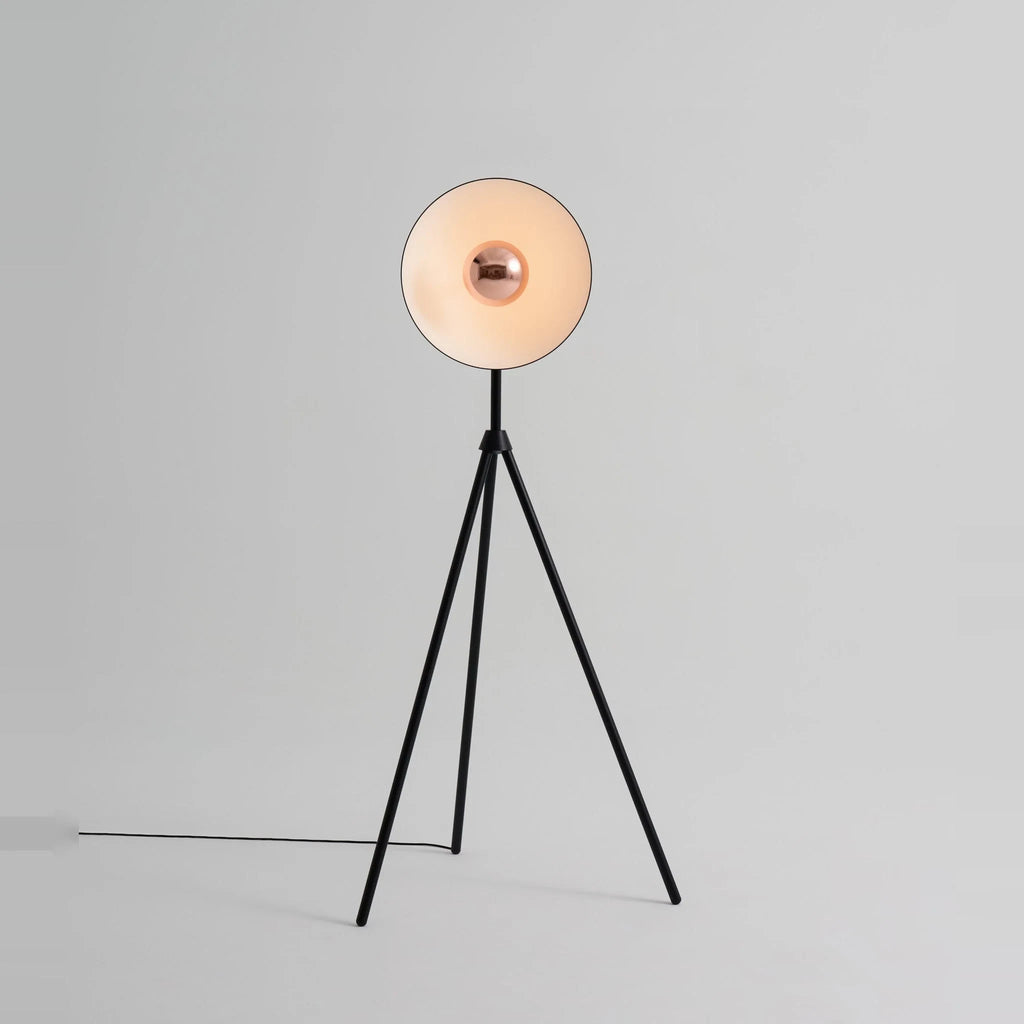 Oversize shade tripod floor lamp with black steel tripod, on a plain background