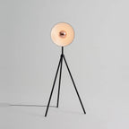 Oversize shade tripod floor lamp with black steel tripod, on a plain background