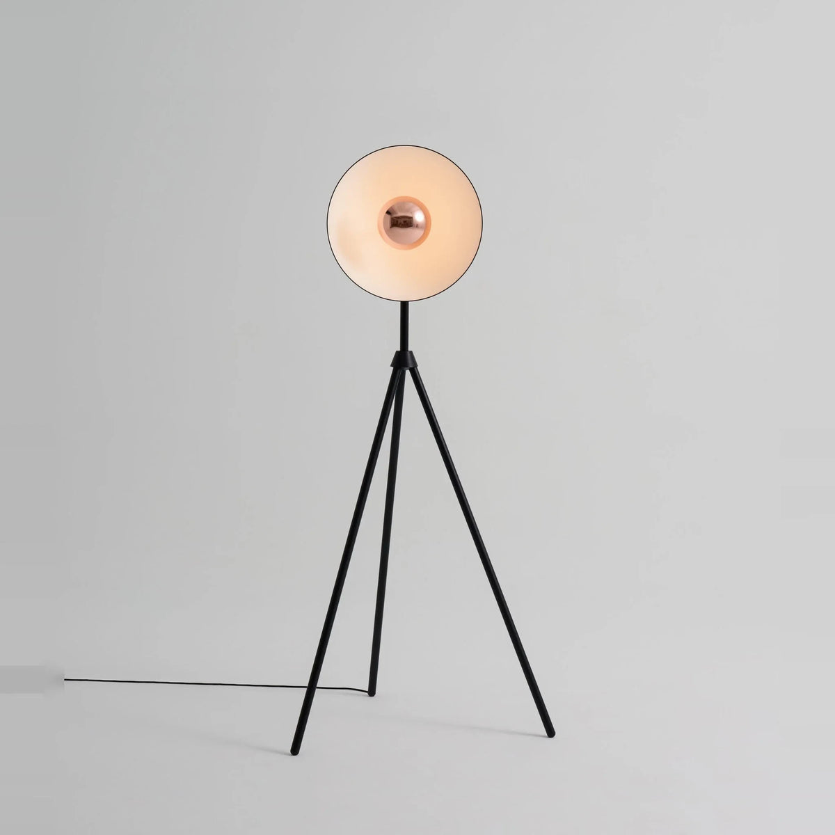 Oversize shade tripod floor lamp with black steel tripod, on a plain background
