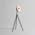 Oversize shade tripod floor lamp with black steel tripod, on a plain background, from the side