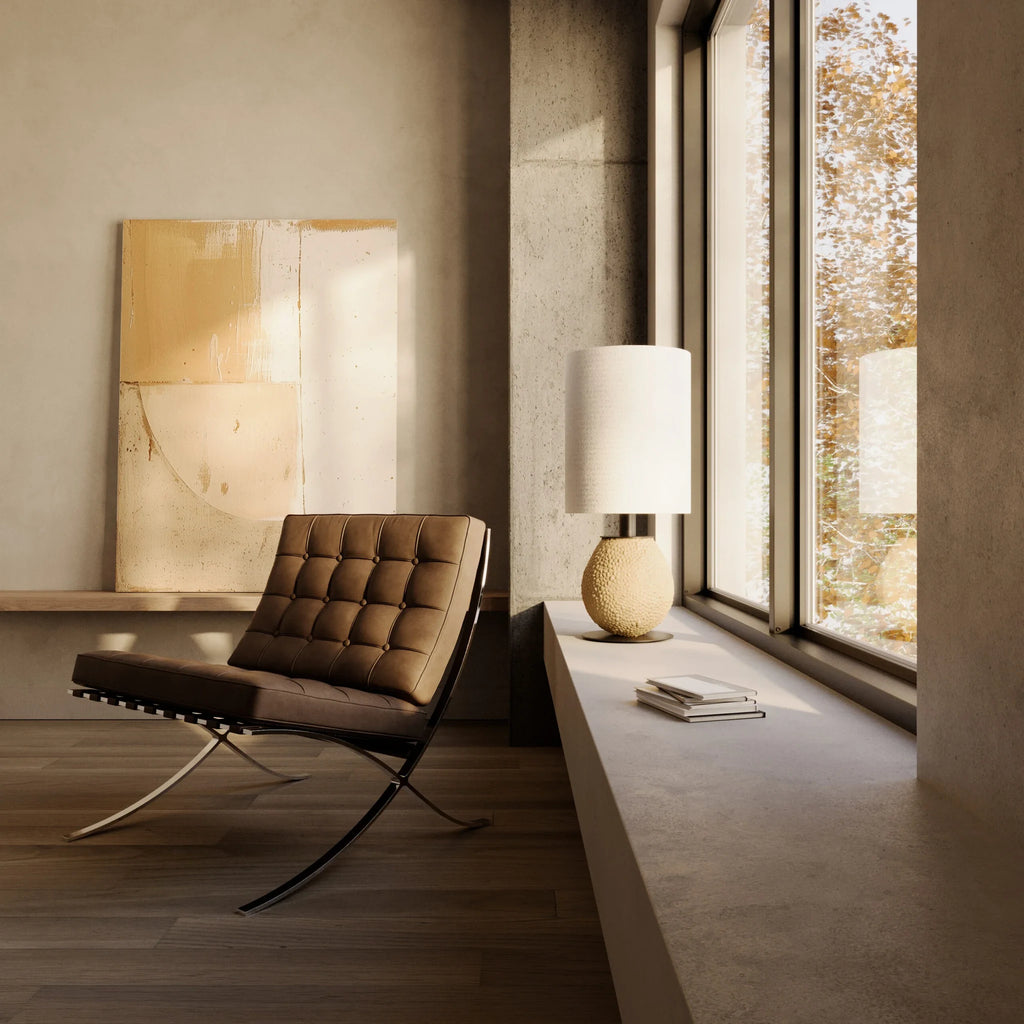 Pebbled ceramic egg-shaped table lamp base, on a low ledge beside a lounge chair, with a shade (sold separately)