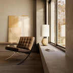Pebbled ceramic egg-shaped table lamp base, on a low ledge beside a lounge chair, with a shade (sold separately)