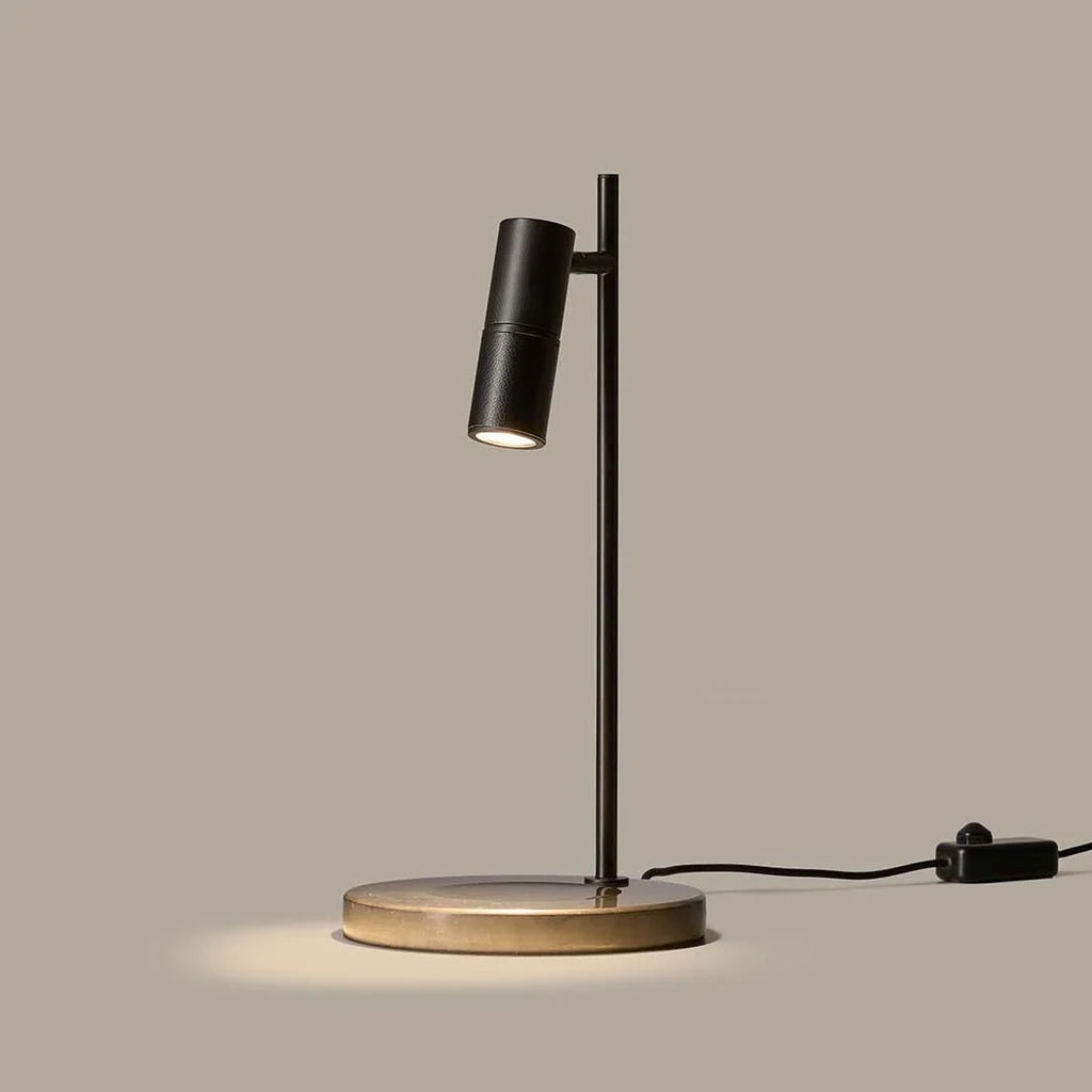 Pivoting spotlight table lamp with leather and ribbed metal head, lit, with a black leather head