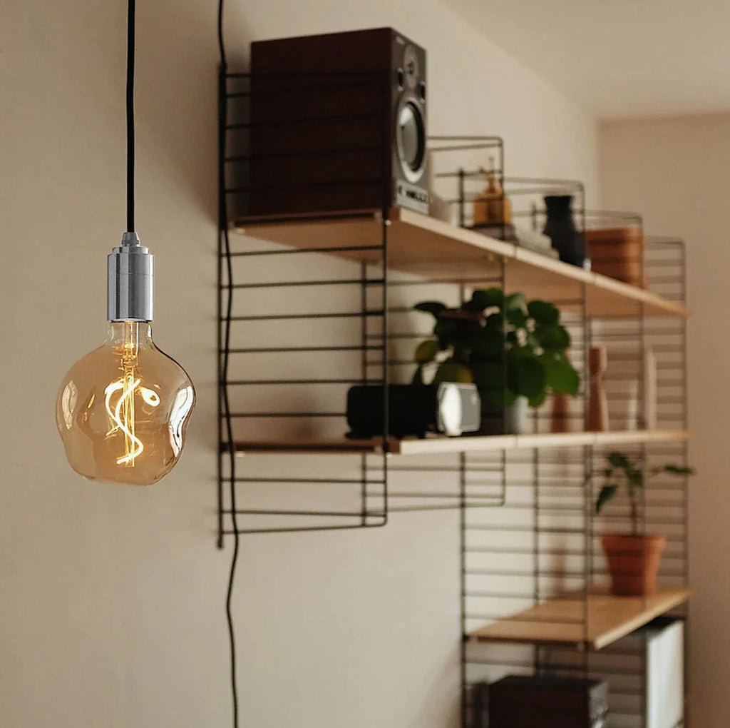 Plug-in bulb holder pendant, with a tinted globe bulb by a shelf