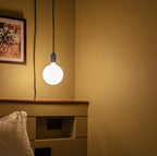 Plug-in bulb holder pendant, with an opal globe bulb by a bed