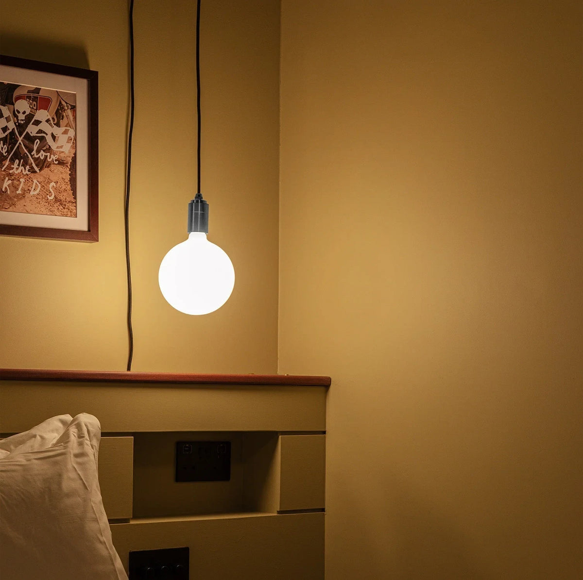 Plug-in bulb holder pendant, with an opal globe bulb by a bed