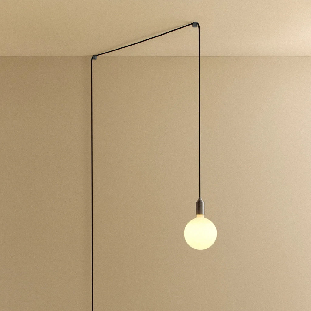 Plug-in pendant with opal globe bulb, graphite, lit, hung from a wall node