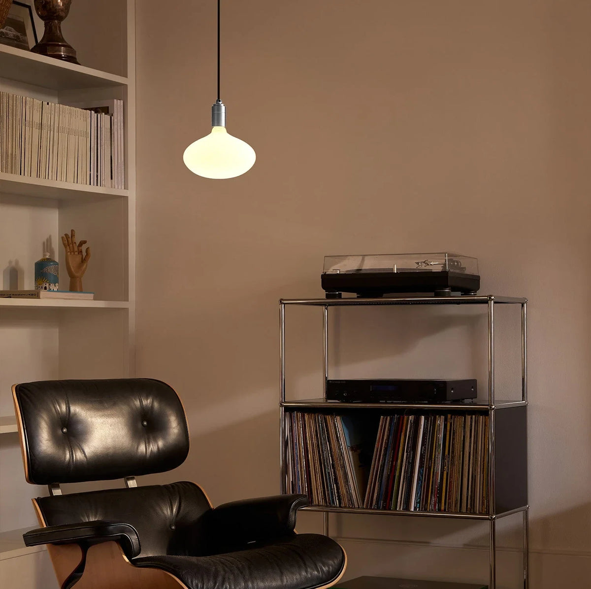 Plug-in pendant with large opal oval bulb, stainless steel, above a leather lounge chair