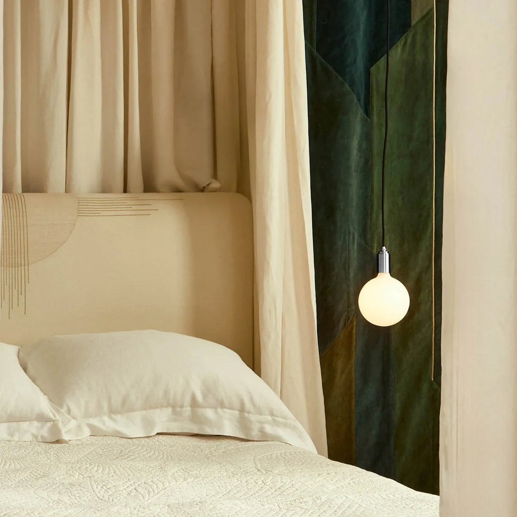 Plug-in pendant with opal globe bulb, stainless steel, beside a bed