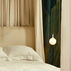 Plug-in pendant with opal globe bulb, stainless steel, beside a bed