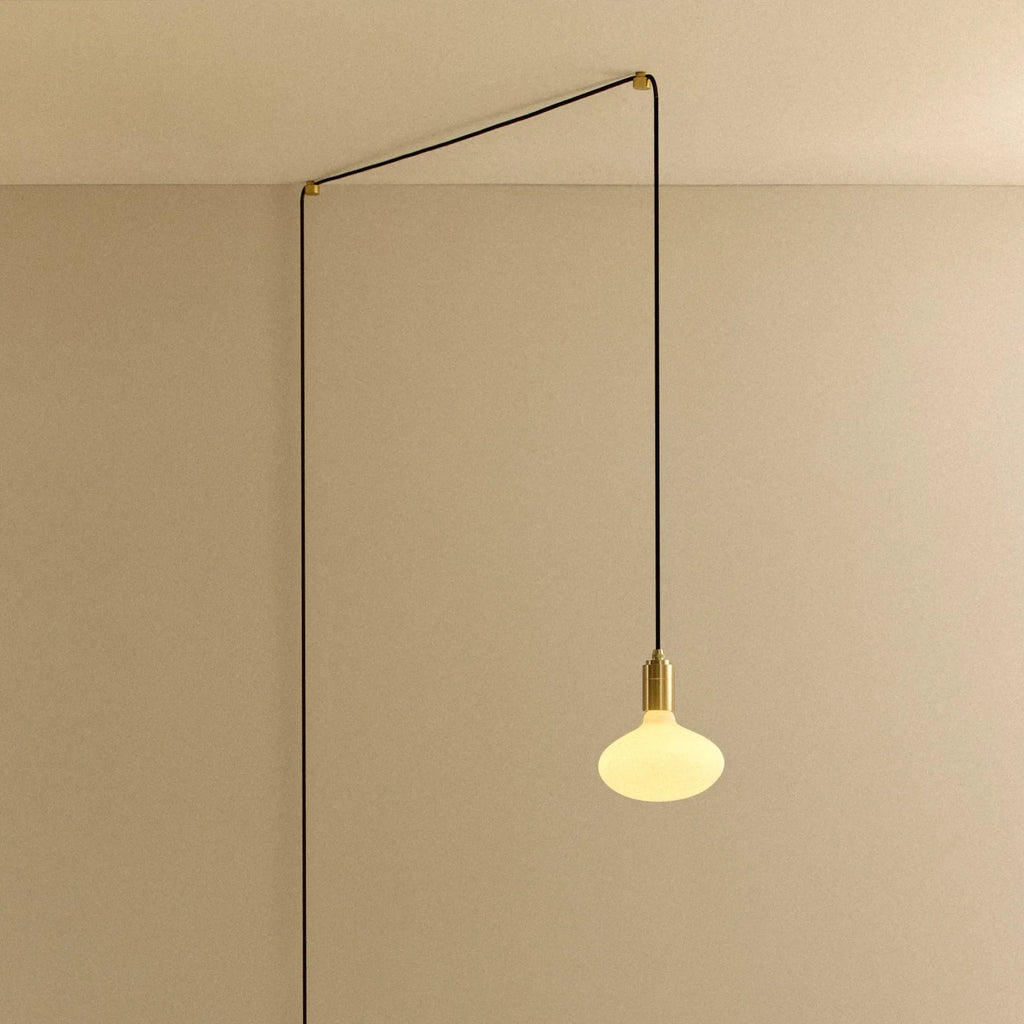 Plug-in pendant with small opal oval bulb, brass, cable routed across wall and ceiling