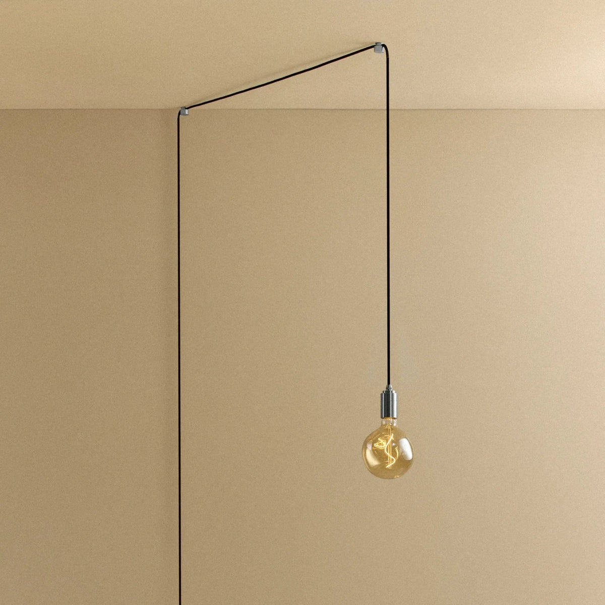Plug-in pendant with small tinted sculptural bulb, stainless steel, cable routed across wall and ceiling