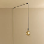Plug-in pendant with tinted glass globe bulb, graphite, lit, hung from a wall node