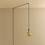 Plug-in pendant with tinted glass globe bulb, graphite, lit, hung from a wall node