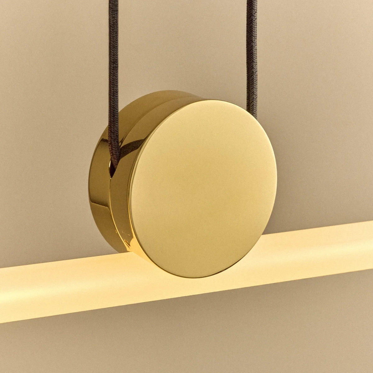 Polished brass linear LED pendant, close-up of the polished brass disc