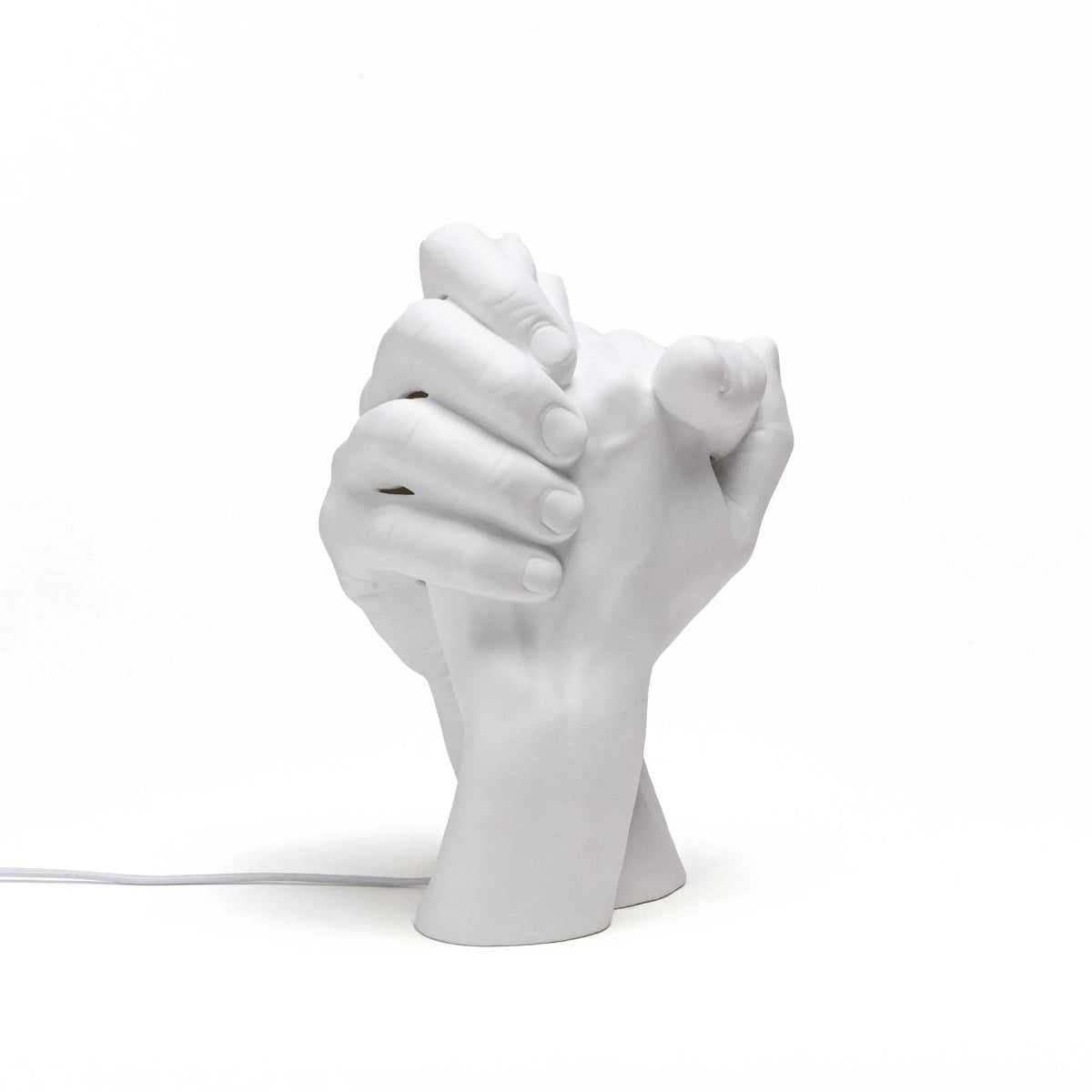 Porcelain clasped hands table lamp, white, unlit, on a plain background