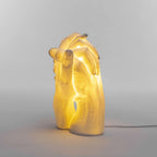 Porcelain clasped hands table lamp, white, lit, glowing warmly