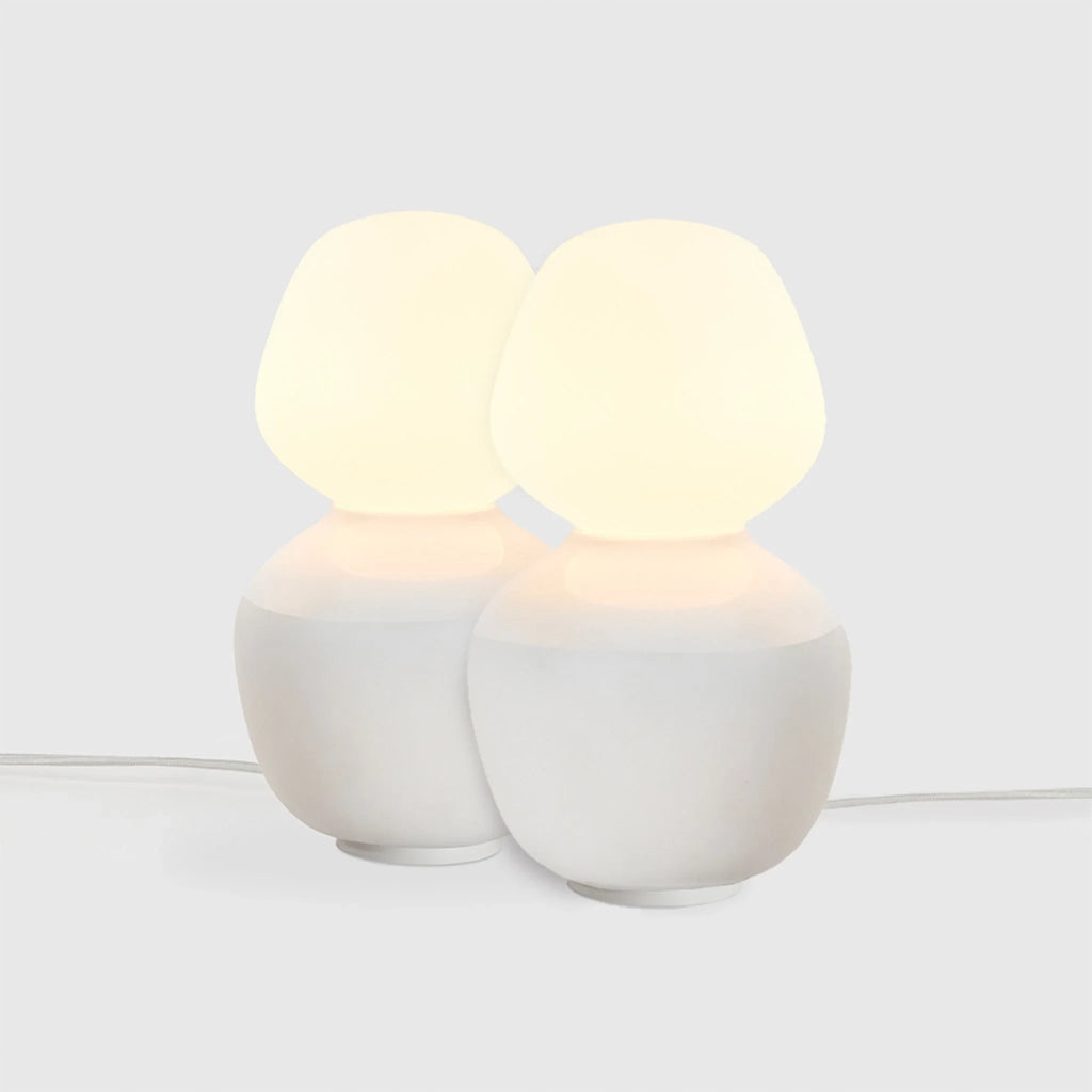 White porcelain table lamp with an angular opal bulb, pair on a pale background