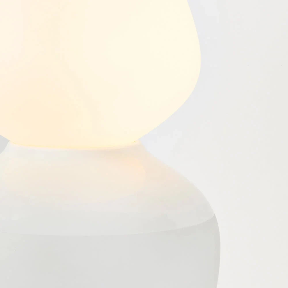 White porcelain table lamp with an angular opal bulb, close-up of the base, lit