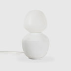 White porcelain table lamp with an angular opal bulb, unlit, on a pale background