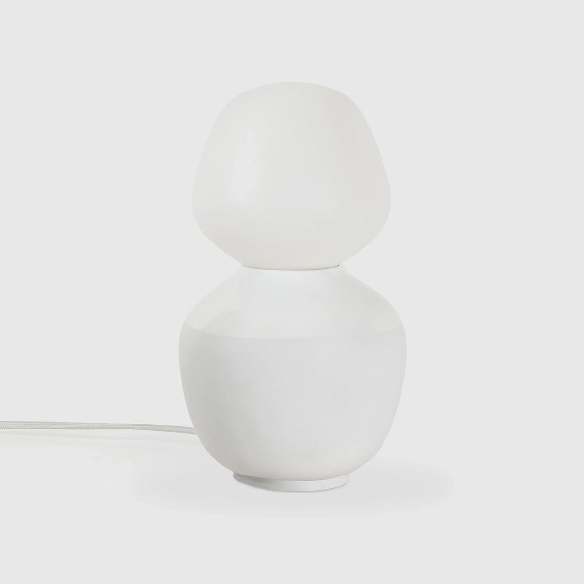 White porcelain table lamp with an angular opal bulb, unlit, on a pale background