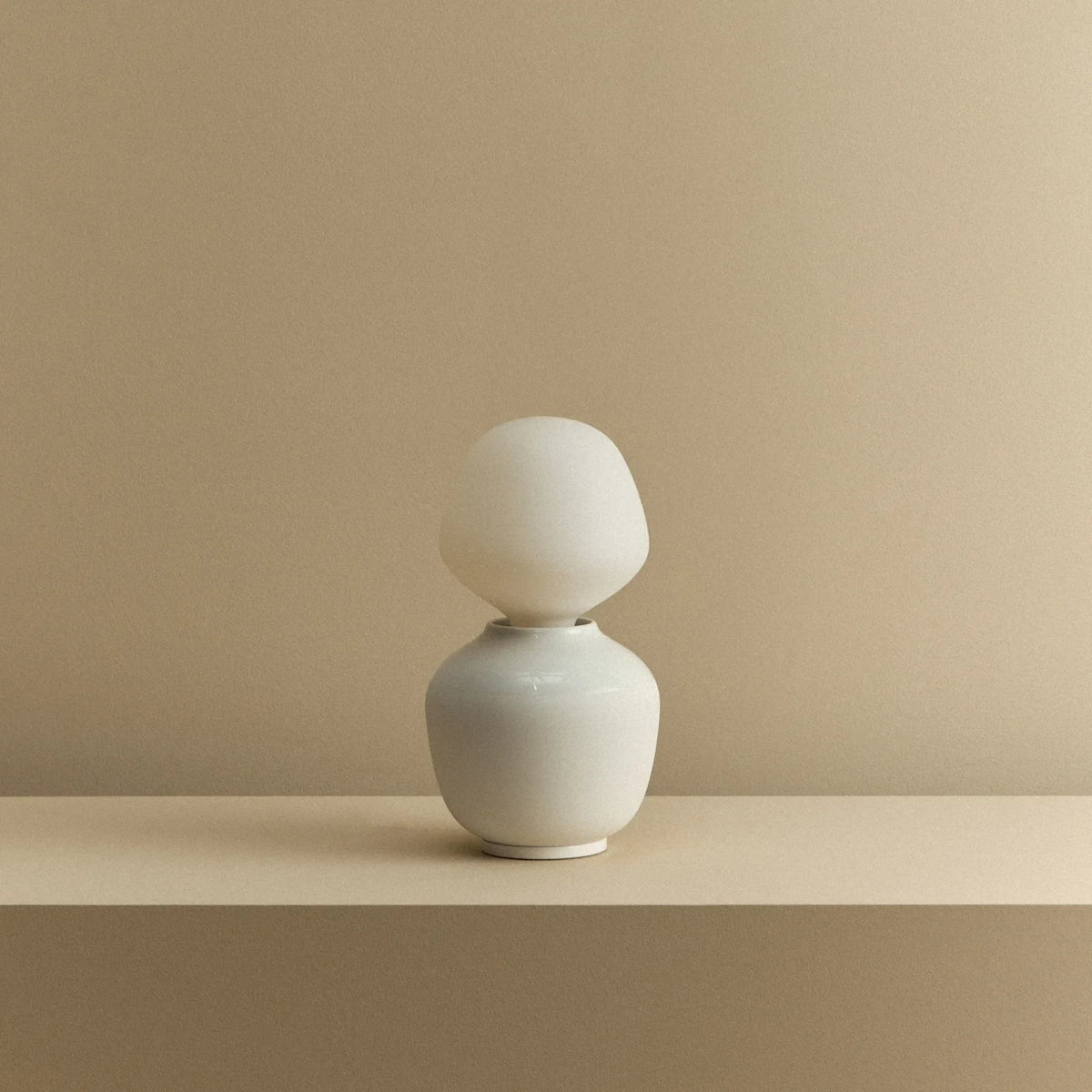 White porcelain table lamp with an angular opal bulb, unlit, on a shelf