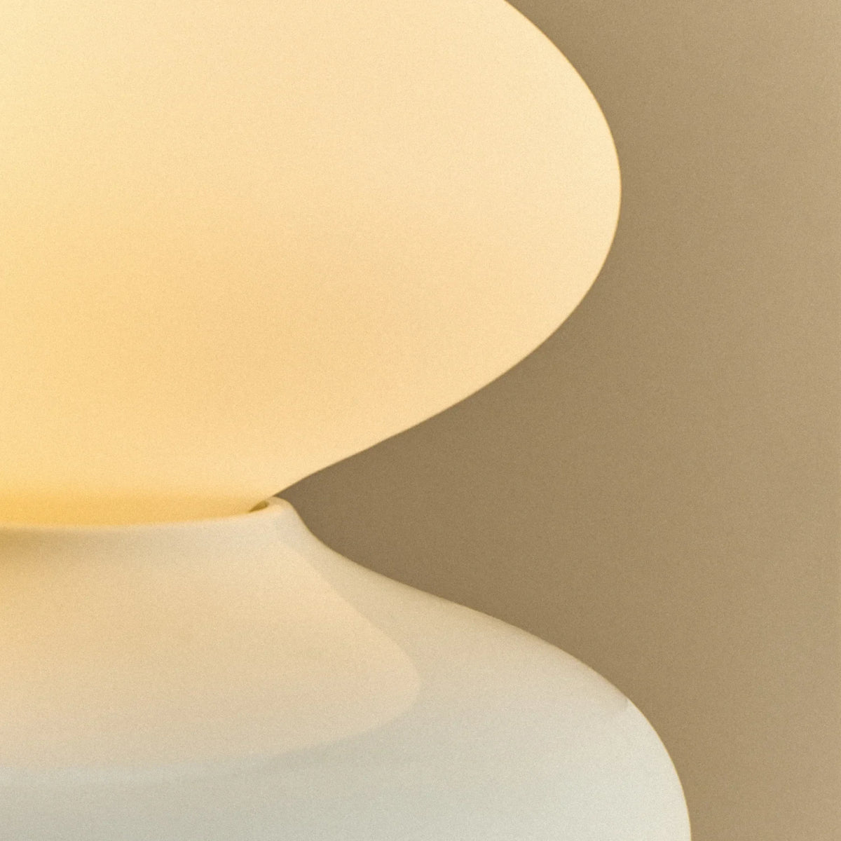 White porcelain table lamp with an oval opal bulb, close-up of the glazed base, lit