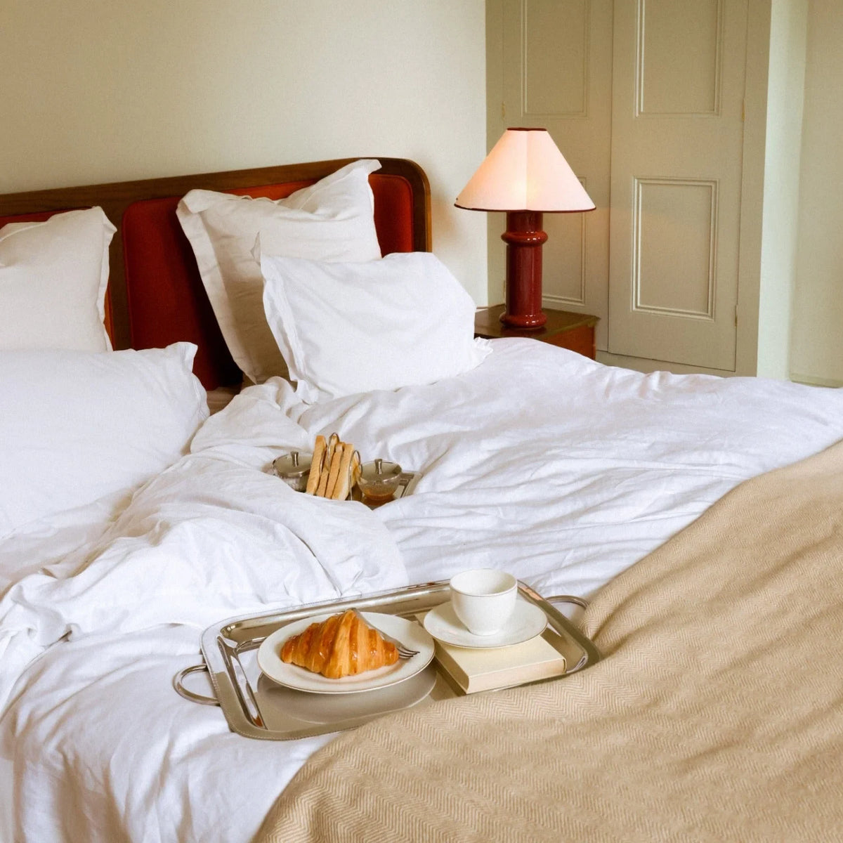 Ceramic table lamp, port red glaze with a folded cotton shade, on a bedside table