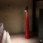 Slim cone cordless table lamp, in red, lit beside books