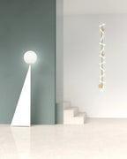 Pyramid base floor lamp with a white glass globe, in white beside a staircase