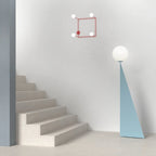 Pyramid base floor lamp with a white glass globe, in light blue beside a staircase