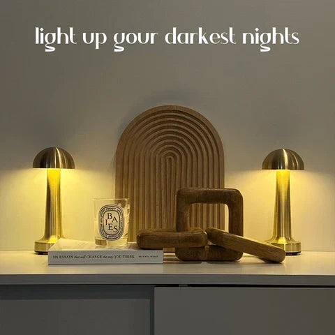 Small mushroom cordless table lamp, a pair in gold, lit on a sideboard