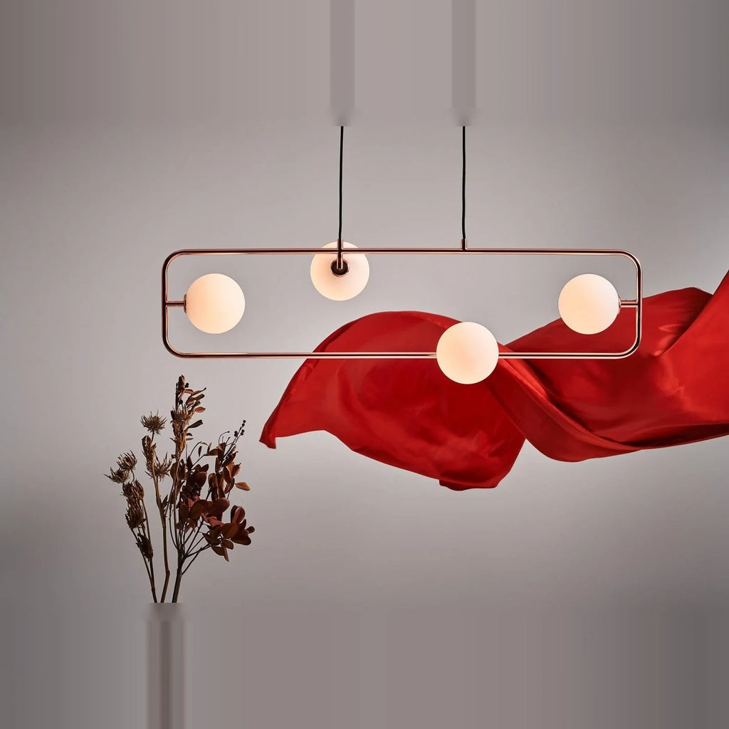 Rectangular Frame Four-Globe Linear Pendant, in copper against a red drape