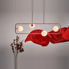 Rectangular Frame Four-Globe Linear Pendant, in copper against a red drape