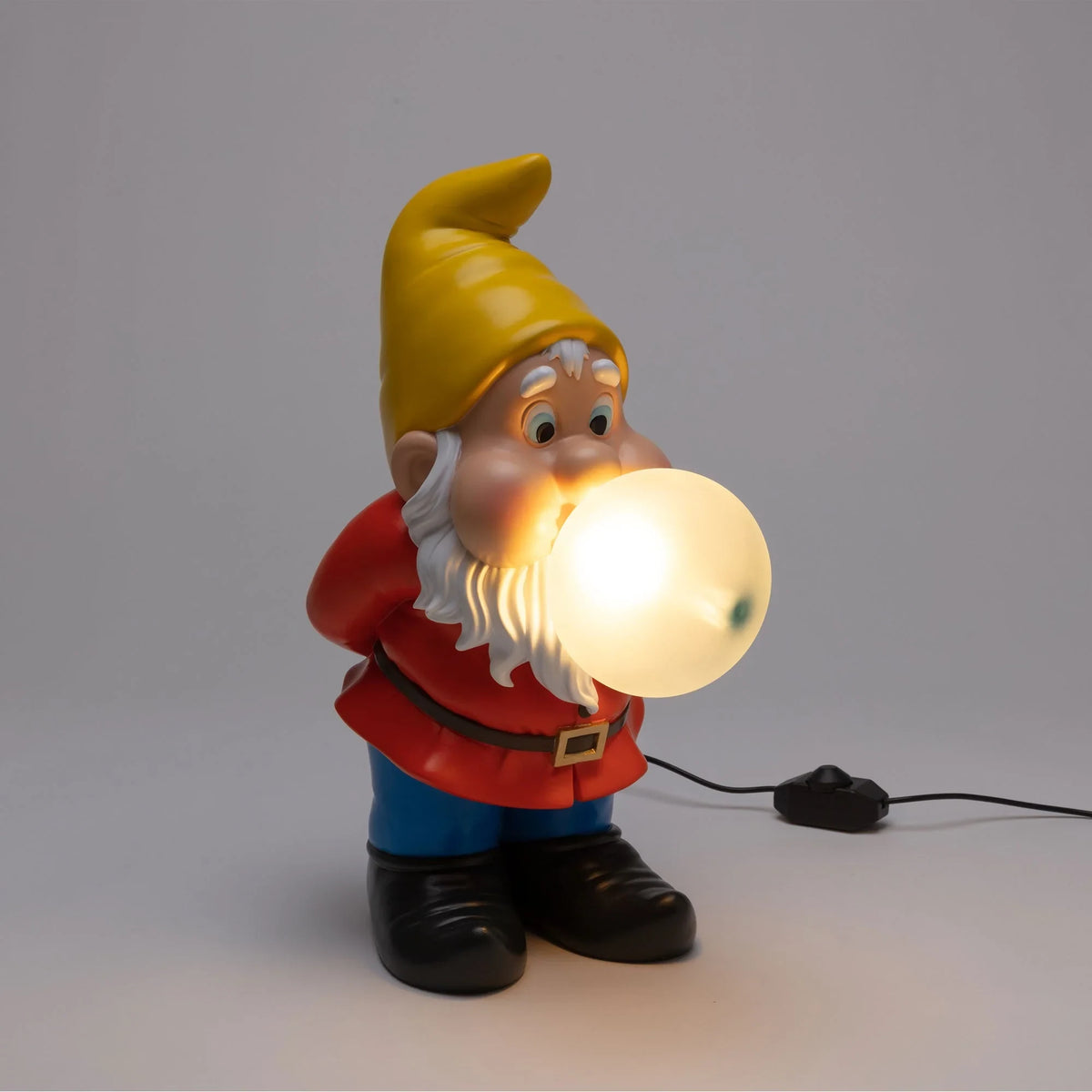 Resin dwarf table lamp blowing a glowing glass bubble, lit, with a glowing bubble