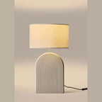 Ridged arch ceramic table lamp, in a pale grey, lit