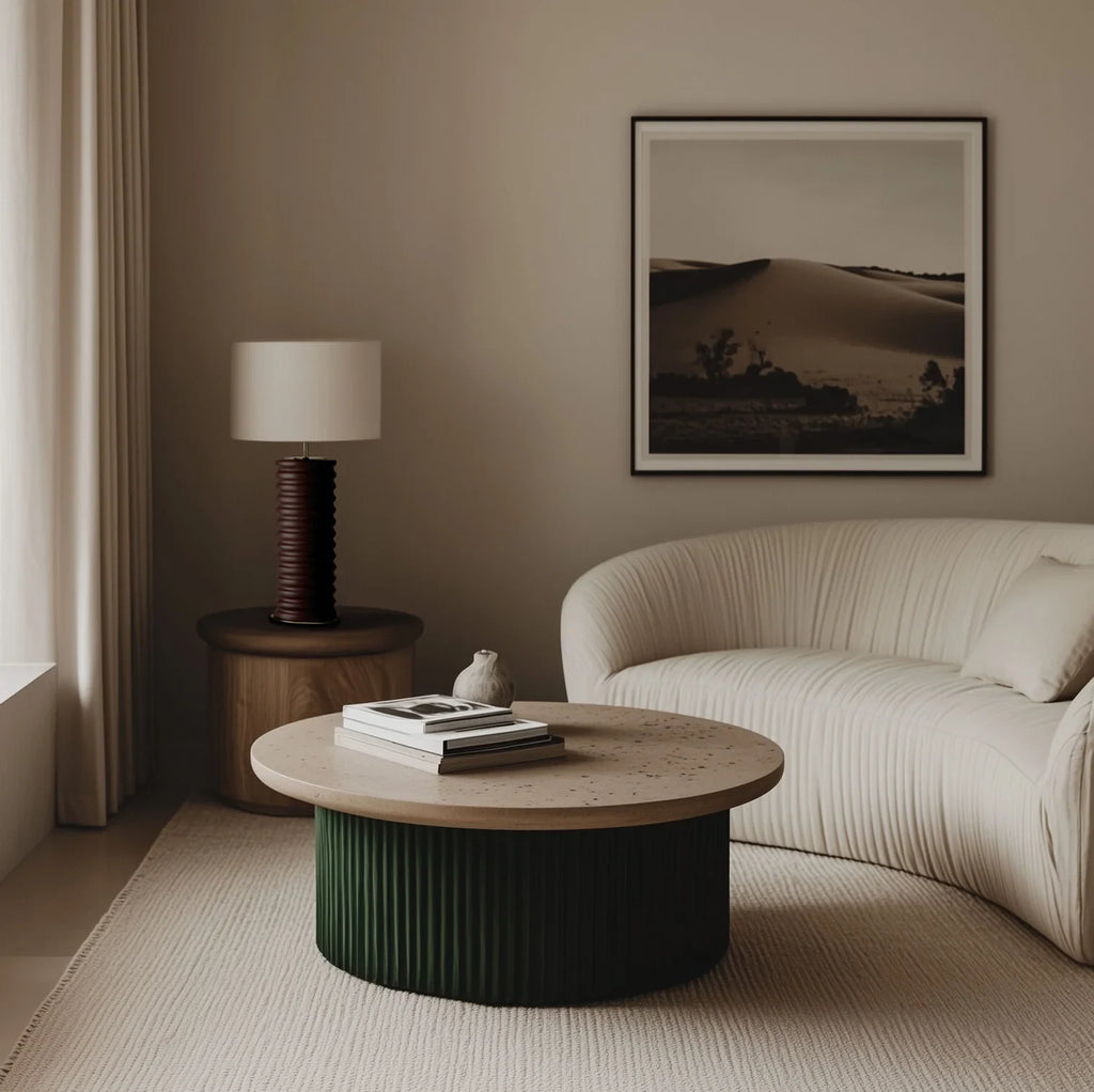 Ridged ceramic cylinder table lamp, in dark green beside a curved sofa