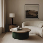 Ridged ceramic cylinder table lamp, in dark green beside a curved sofa