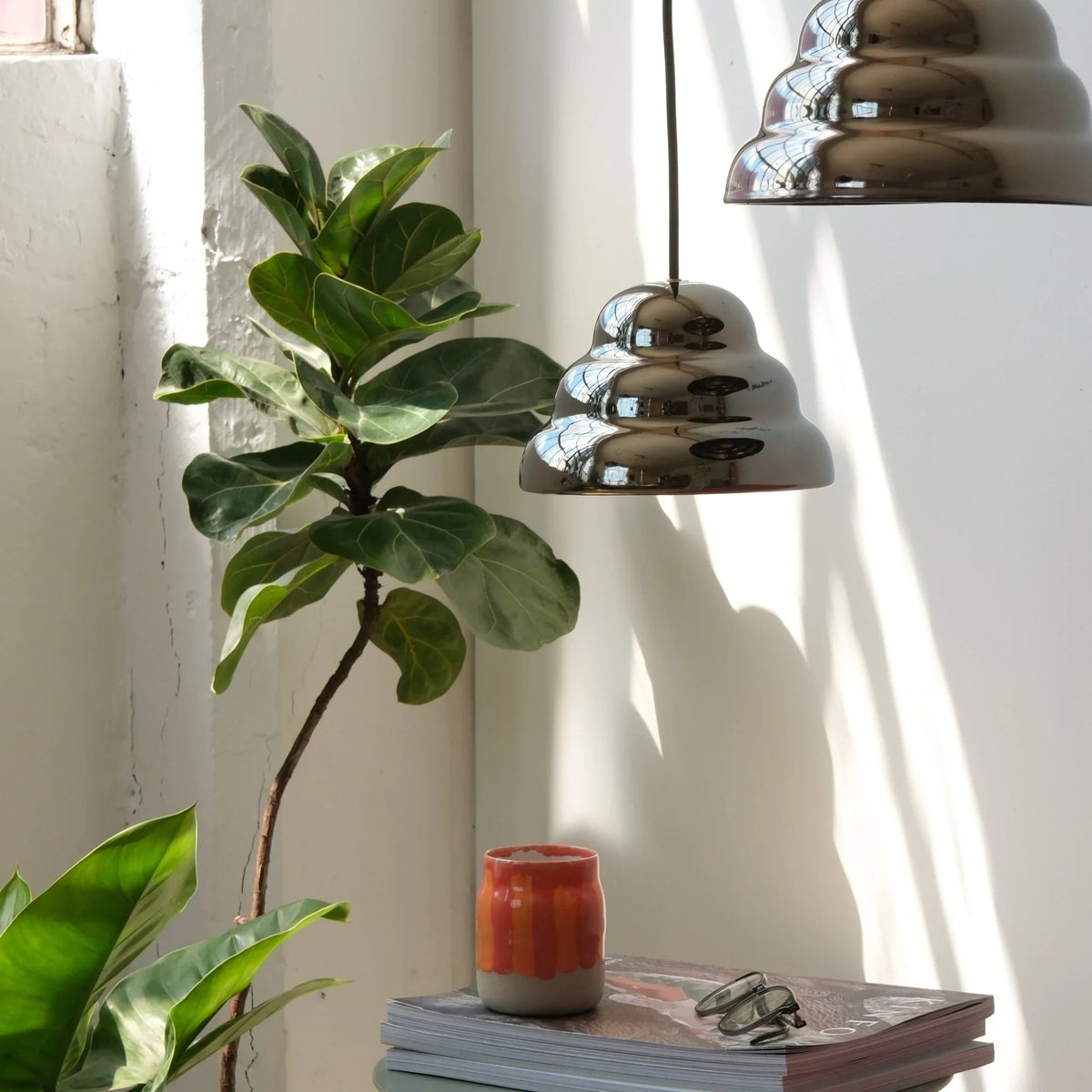 Rippled chrome-glaze stoneware pendant, above a side table with plants