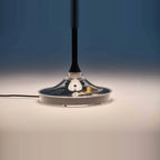 Black disc table lamp with rotating dimmer base, close-up of the base